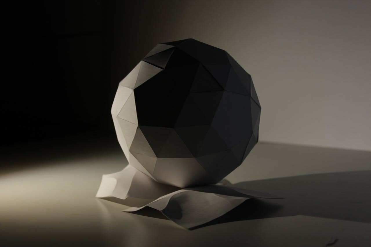 Minimalist geometric sculpture under artistic lighting, emphasizing shape and shadow.