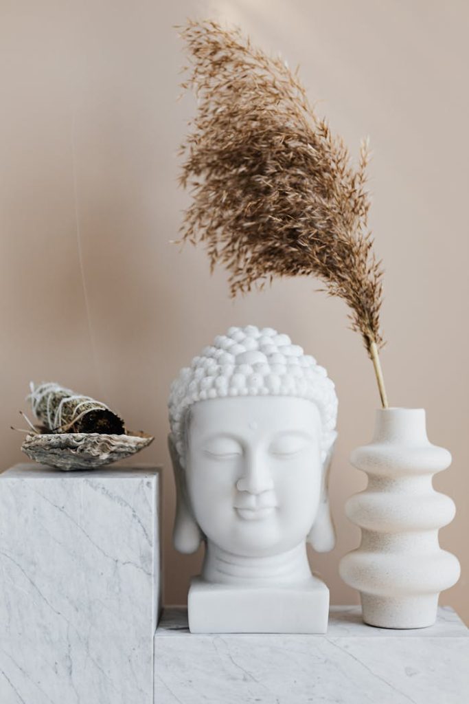 Tranquil interior scene showcasing a Buddha bust with a vase and sage on a shelf.